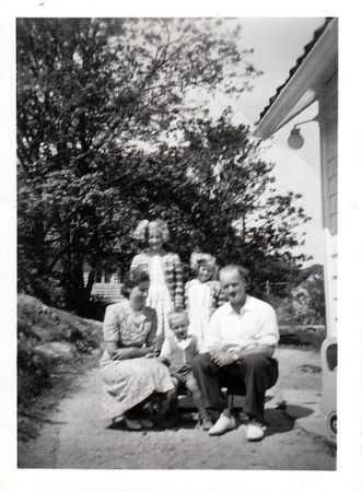 Familien samlet utenfor huset en solskinnsdag ca. 1950